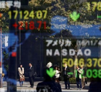 People are reflected in a display showing the Nikkei average (top in L) and the NASDAQ average of the U.S outside a brokerage in Tokyo, Japan, November 7, 2016. REUTERS/Kim Kyung-Hoon